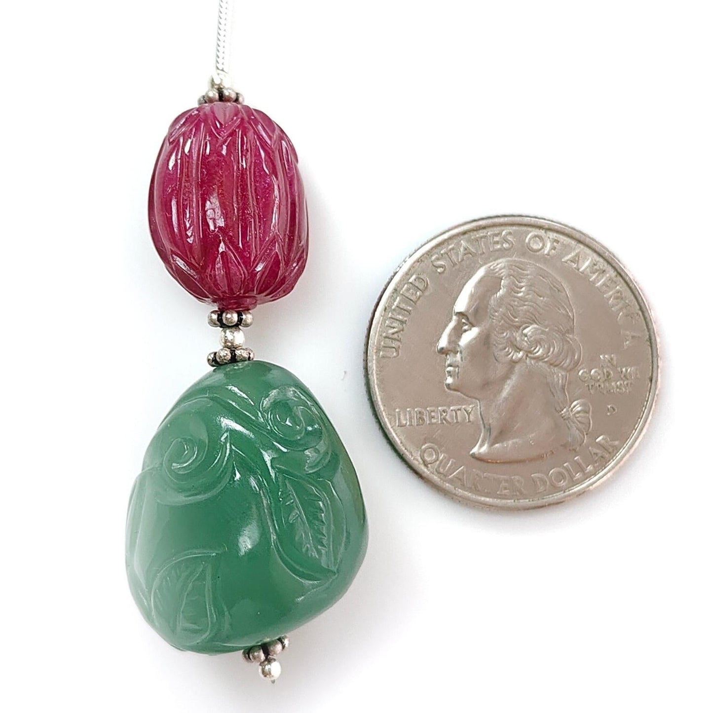 Two colored beads next to a quarter for size comparison on a white background