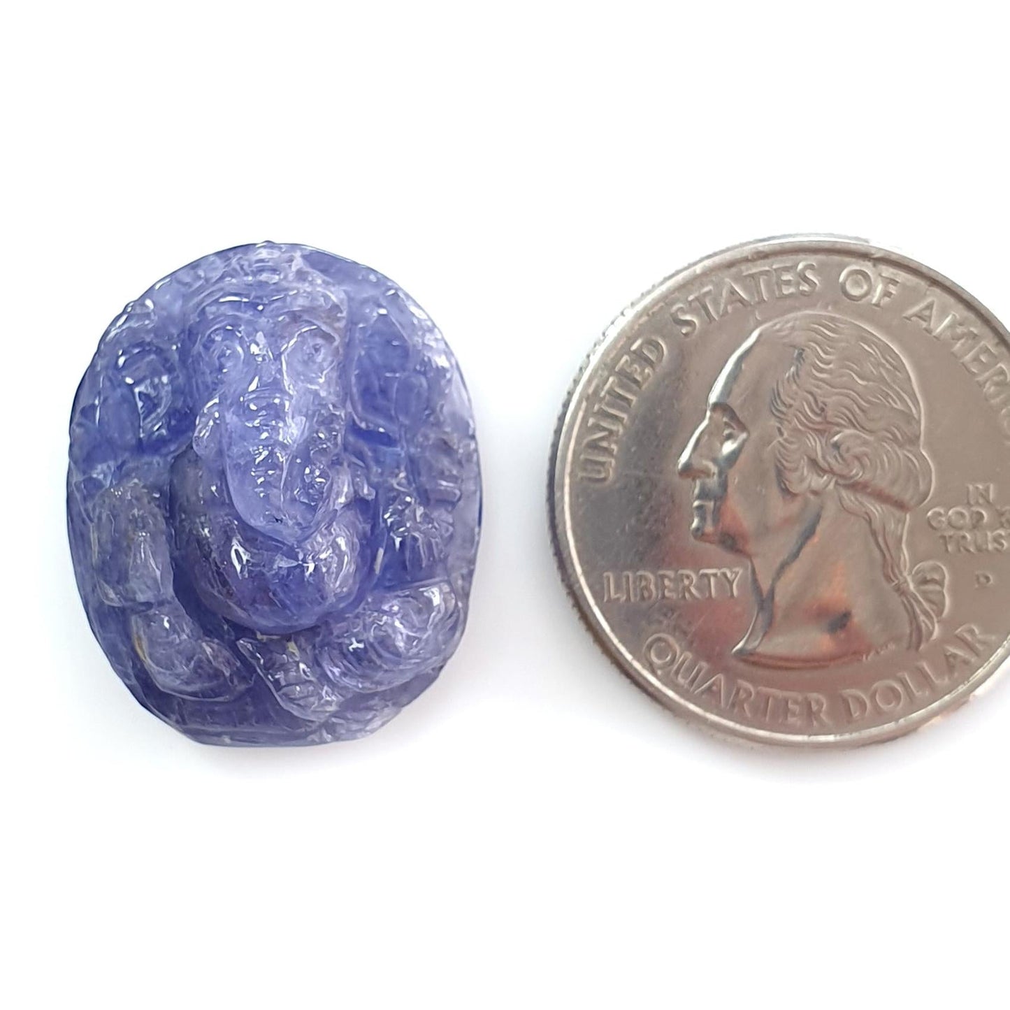 Purple gemstone with carvings next to a U.S. quarter dollar coin on a white background